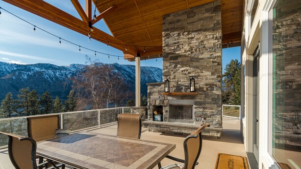Une terrasse extérieure avec une cheminée en pierre, une table et des chaises.