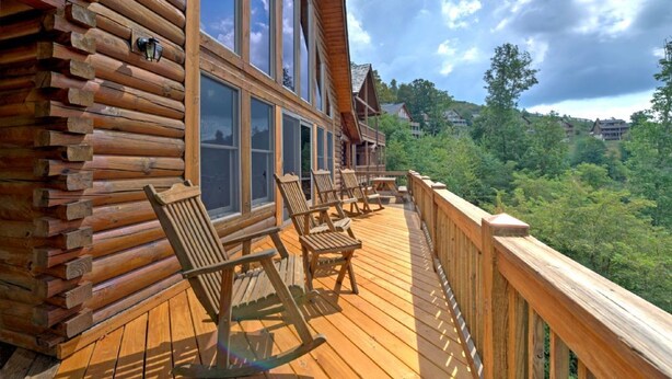 Une cabane en bois avec une terrasse, de grandes fenêtres et un espace salon extérieur.