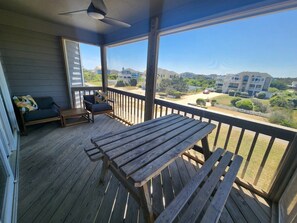 A wooden deck with a table and chairs, overlooking a residential area with houses and greenery.
