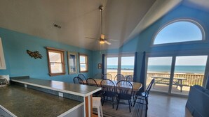 A kitchen with a dining area, a ceiling fan, and a view of the beach.