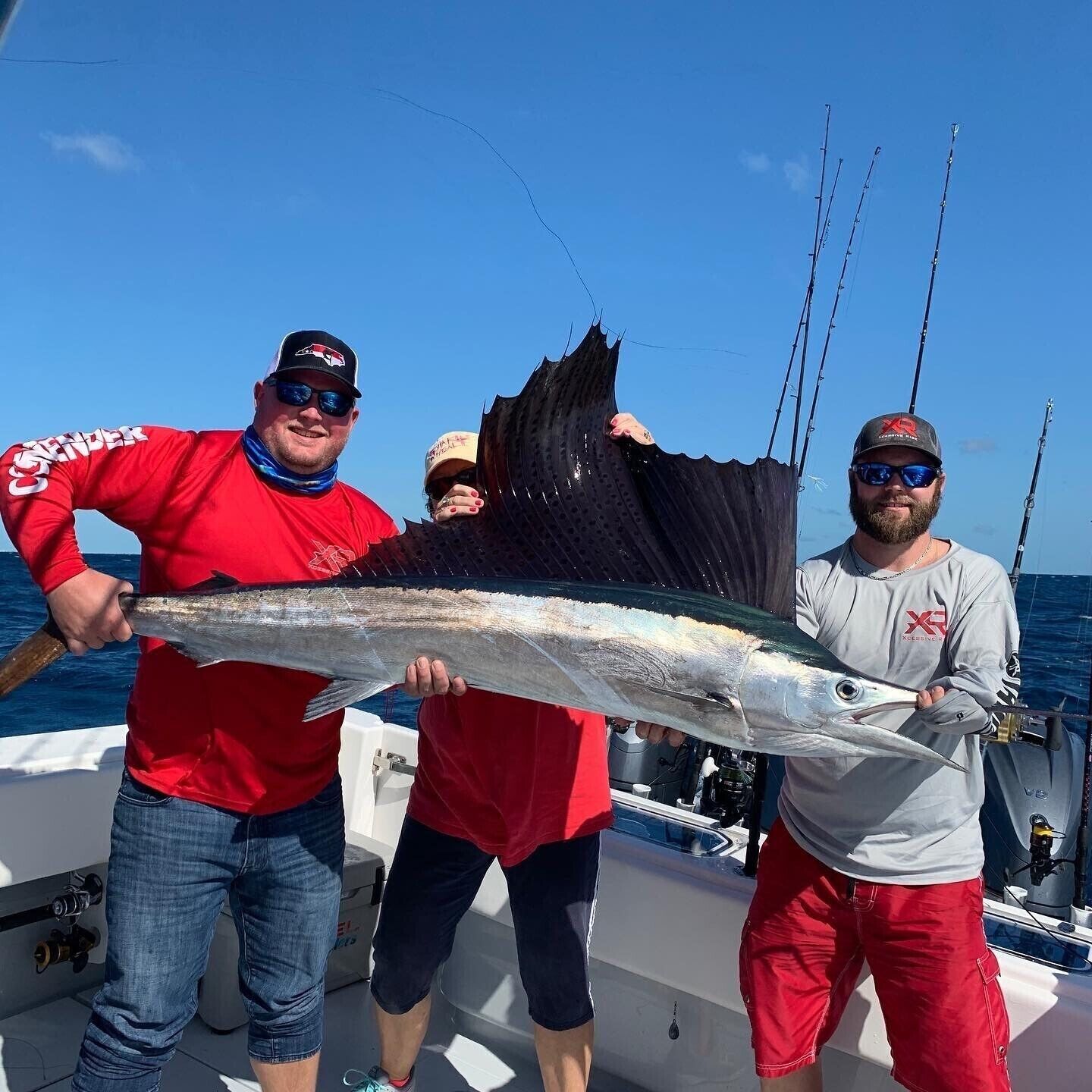 Trois personnes se trouvent dans un bateau et tiennent un gros poisson.
