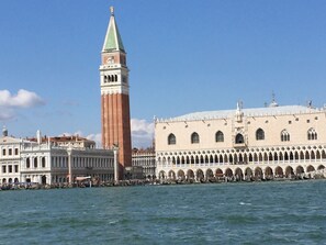 Un edificio histórico con una torre destacada y una serie de arcos a lo largo del paseo marítimo.