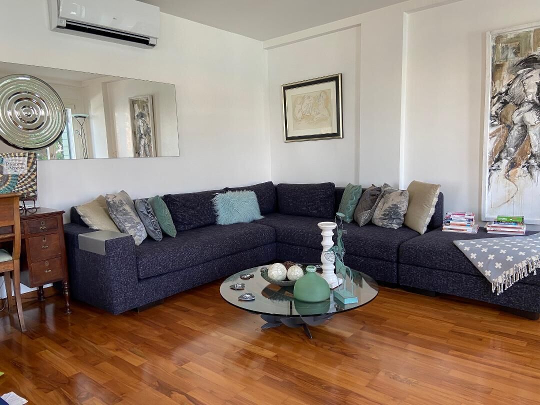 A living room with a dark blue sectional sofa, a glass coffee table, and a wooden floor.