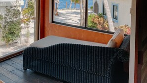 Ein Zimmer mit einem großen Bogenfenster mit Blick auf einen Strand und Palmen.