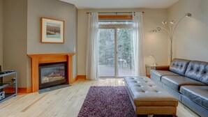 Ein Wohnzimmer mit Kamin, einer Couch, einem Teppich und einem großen Fenster mit Vorhängen.