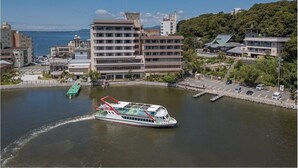 Un río con un transbordador y edificios a lo largo de la orilla.