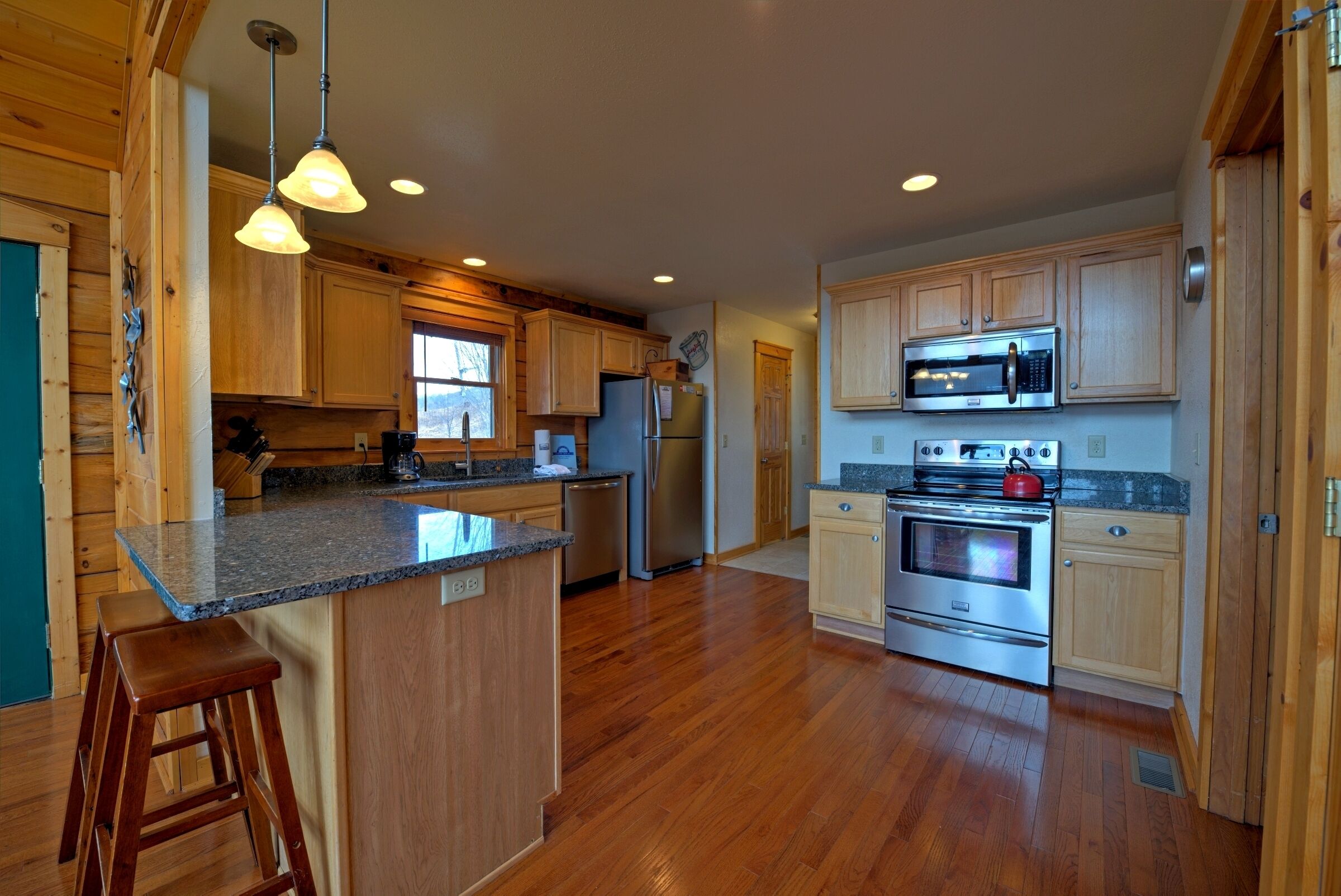 A spacious kitchen with wooden cabinets, stainless steel appliances, and a granite countertop.