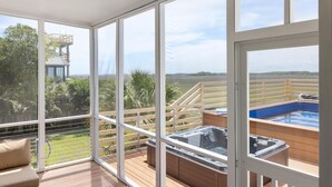 Un balcon spacieux avec un jacuzzi, une terrasse en bois et une vue sur un paysage luxuriant.