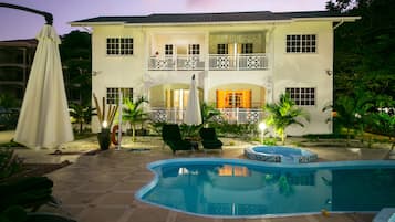 A two-story house with a swimming pool, outdoor seating, and a balcony.