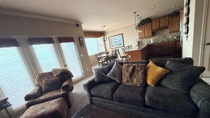 A living room with a sofa, armchair, and coffee table. There is a dining area with a table and chairs in the background. - Relax In Luxury On Table Rock Lake, Close To Branson (Hollister)