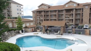 A pool area with lounge chairs and a barbecue grill, surrounded by a stone wall and a wooden deck. - Relax In Luxury On Table Rock Lake, Close To Branson (Hollister)