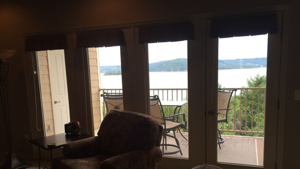 A room with a view of a lake through large sliding glass doors, a sofa, and a small table. - Relax In Luxury On Table Rock Lake, Close To Branson (Hollister)
