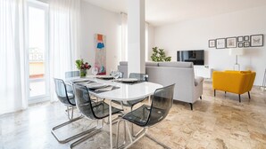 Ein modernes Wohnzimmer mit Essbereich, einer Couch, einem Fernseher und einem gelben Sessel.