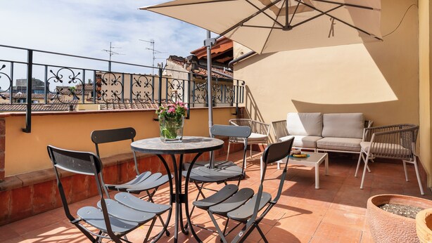 Eine Dachterrasse mit Tisch, Stühlen, einer Couch und einem Sonnenschirm.