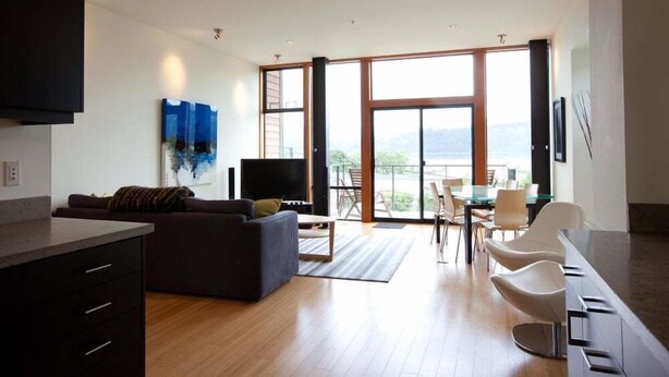 Una sala moderna con un sofá, televisor y comedor con sillas y una mesa.