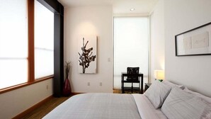 Una habitación de hotel con una cama grande, un escritorio, una silla y obras de arte en las paredes.