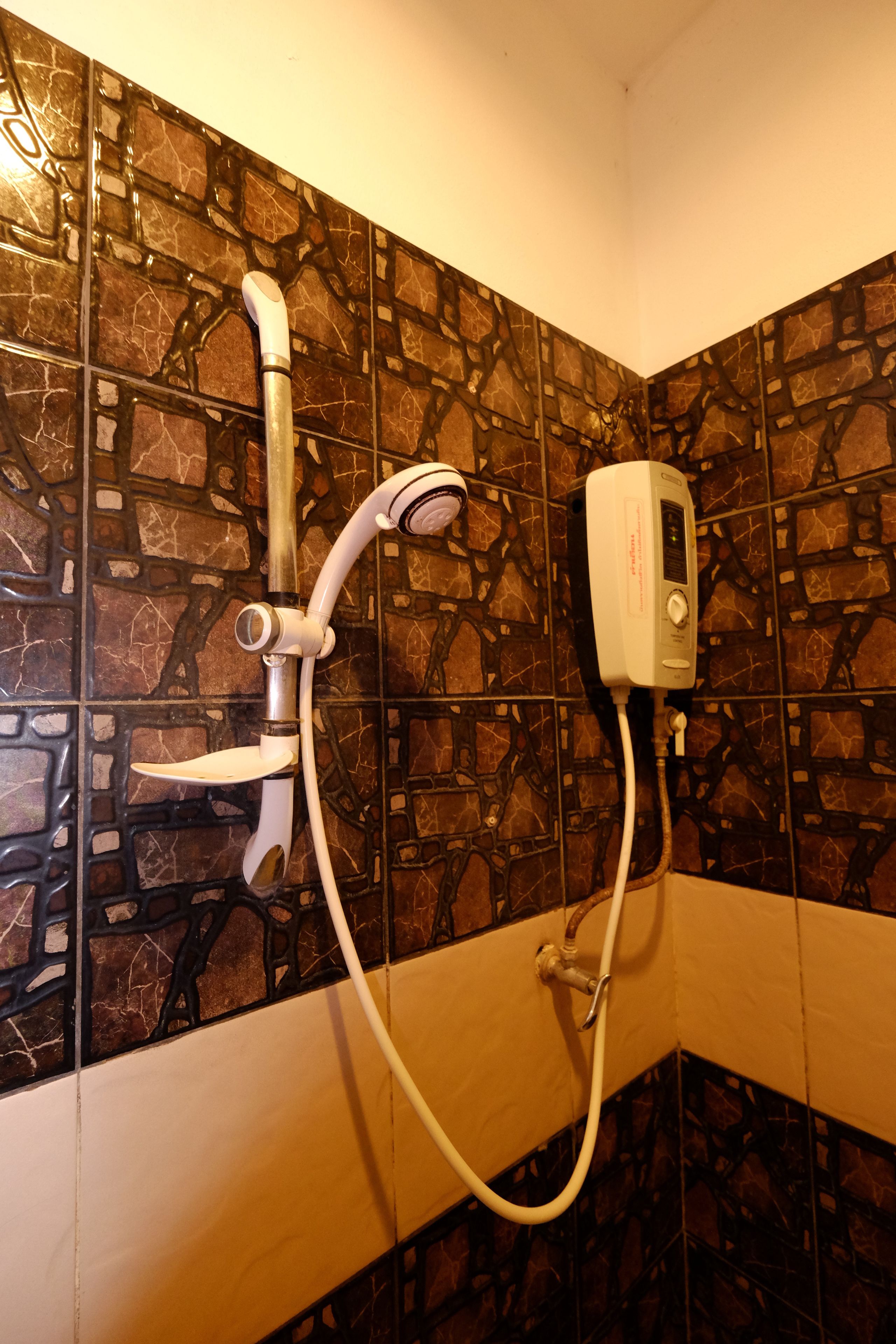 Un baño con ducha, cabezal de ducha de mano y panel de control en la pared.