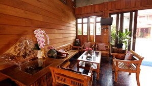 A wooden interior with wooden furniture, a television, and large windows.