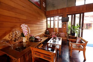 Un interior de madera con muebles de madera, un televisor y ventanas grandes.