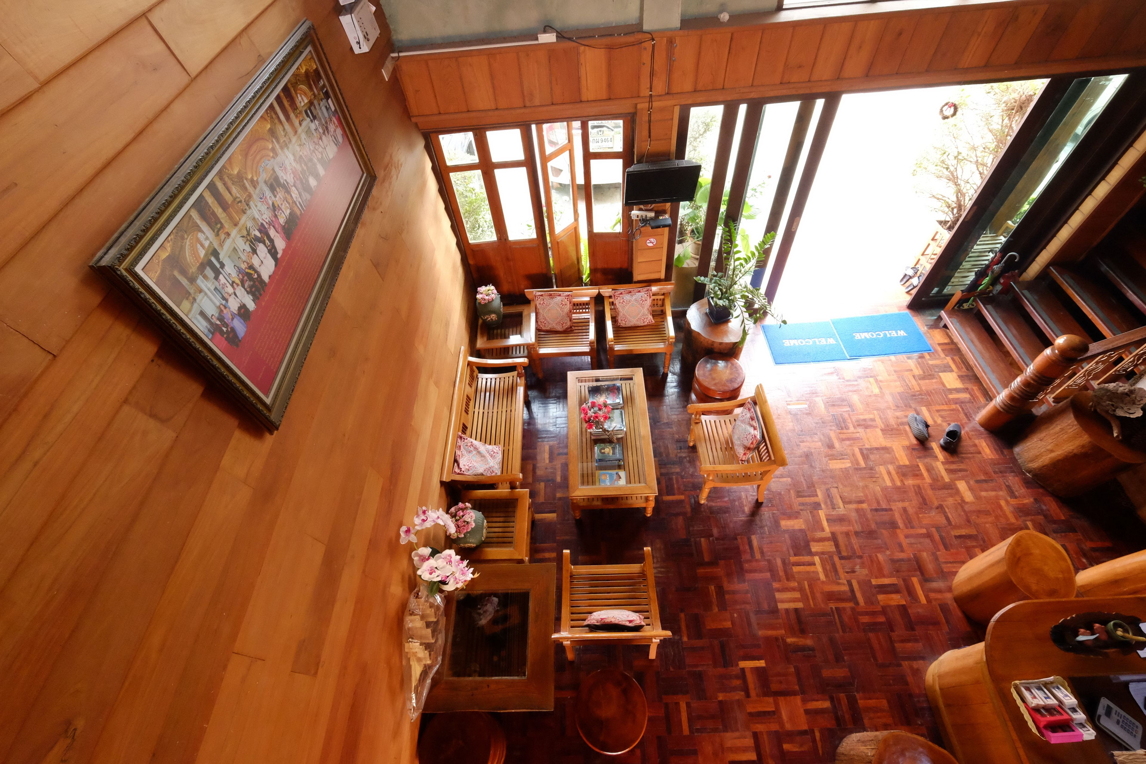 A wooden-floored room with a framed picture, wooden furniture, and a welcome mat.