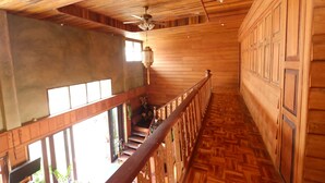 A wooden interior with a staircase, wooden walls, and a ceiling fan.