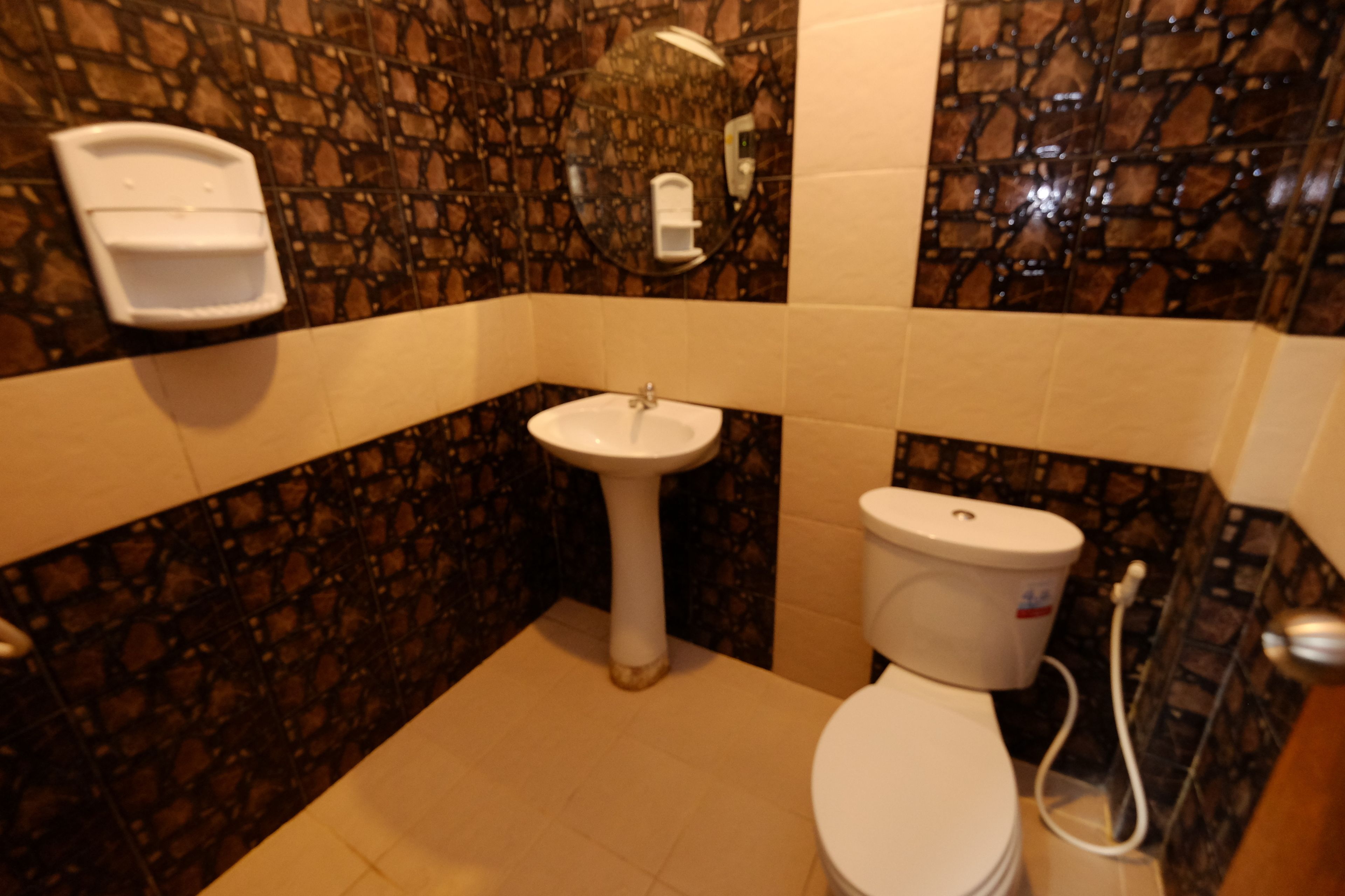 Une salle de bain avec un lavabo blanc, des toilettes et un miroir.