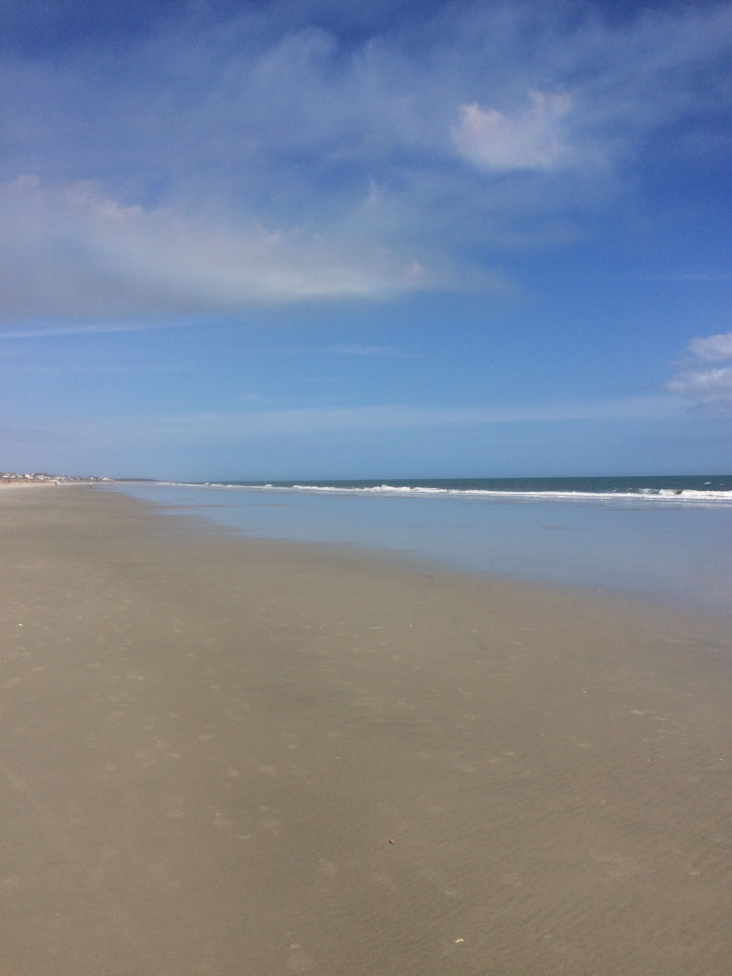 Ein Strand mit breitem Sandstrand und blauem Himmel.