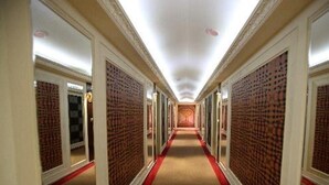 Un largo pasillo estrecho con alfombra roja, flanqueado por paredes con diseño de ladrillo.