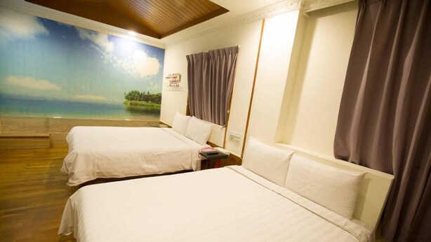 Une chambre d’hôtel avec deux lits, une fresque représentant une scène de plage et un plancher en bois.
