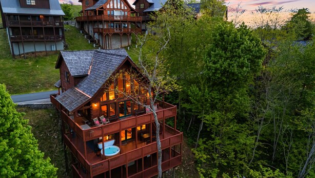 A multi-story log cabin with a deck, a hot tub, and a view of the surrounding forest. - Skylands by Carolina Mornings | Hot Tub + Biltmore Pass 8 mins to Hatley Pointe (Mars Hill)