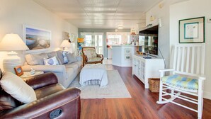 A spacious living area with a sofa, armchair, and a dining area with a kitchen counter.