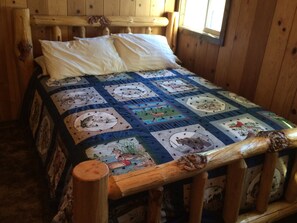 Rest in comfort on this cozy bed with a unique quilt featuring wildlife-themed patches.