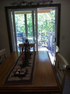 Enjoy meals in this dining area with a table for four, overlooking lush greenery through a sliding glass door.