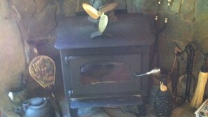 A stone fireplace with a wood stove, a kettle, and a broom.