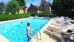 Une piscine avec des chaises longues et une maison en arrière-plan.