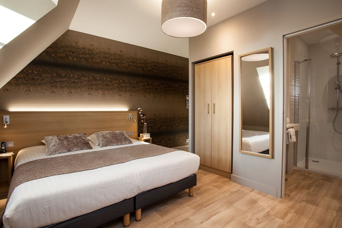 Un dormitorio moderno con una cama grande, un vestidor, zona de ducha y un tragaluz.