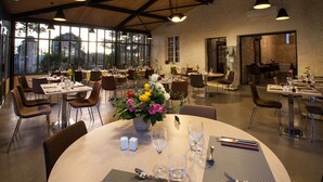 Un vaste espace dédié à la salle à manger, avec de nombreuses tables et chaises, de grandes fenêtres offrant une vue sur l’extérieur et un plafond en bois rustique.