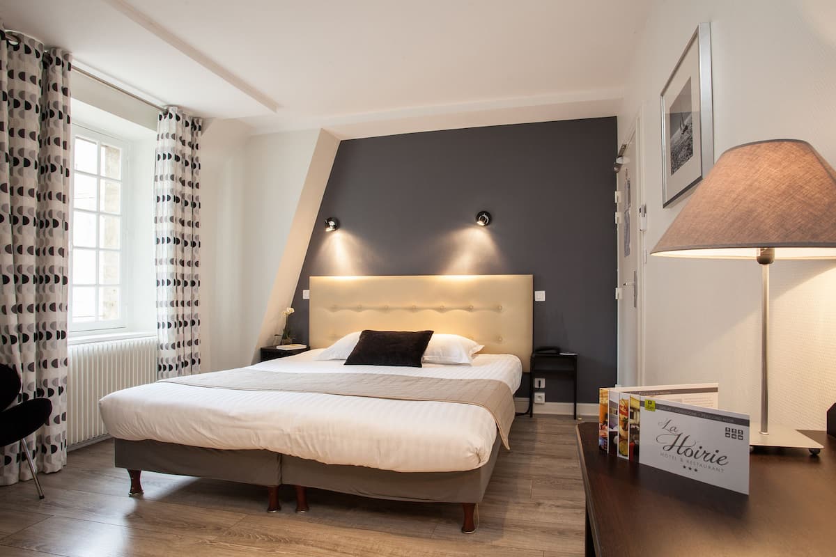 Una habitación de hotel con una cama grande, una mesita de noche, una lámpara y un letrero del Restaurante Hotel La Horie.