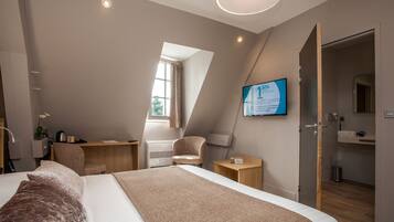 Una habitación de hotel moderna con una cama grande, un escritorio, una silla y un baño visible a través de una puerta abierta.
