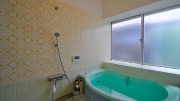 A bathroom with a bathtub, a shower, and a window.