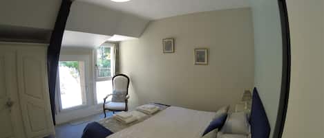 A bedroom with a bed, a chair, a window, and a door.