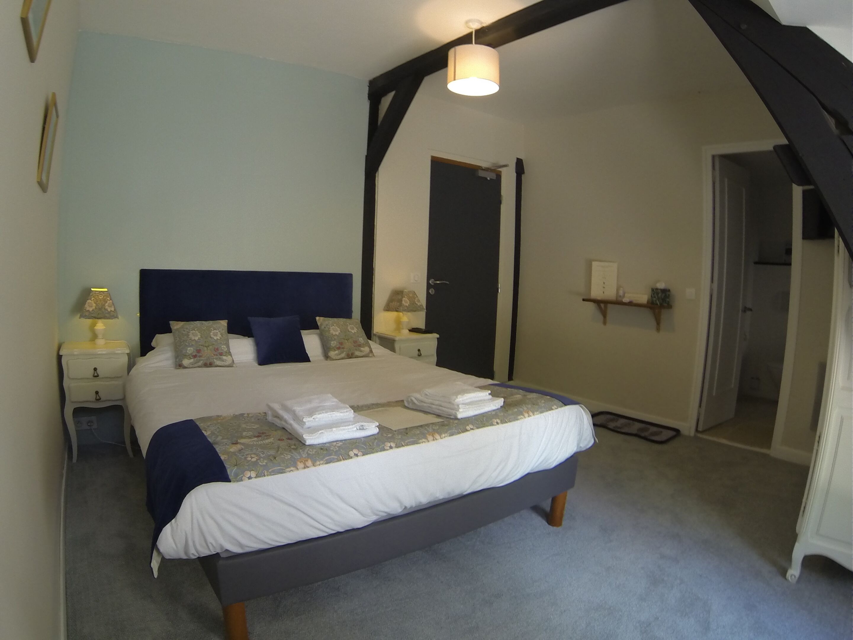 A bedroom with a bed, bedside tables, a lamp, a door, and a shelf.