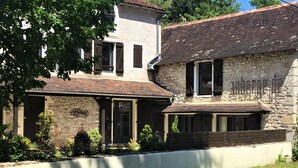 A stone building with a tiled roof, a wooden fence, and a paved road in front. - Auberge de la Sagne (Cabrerets)