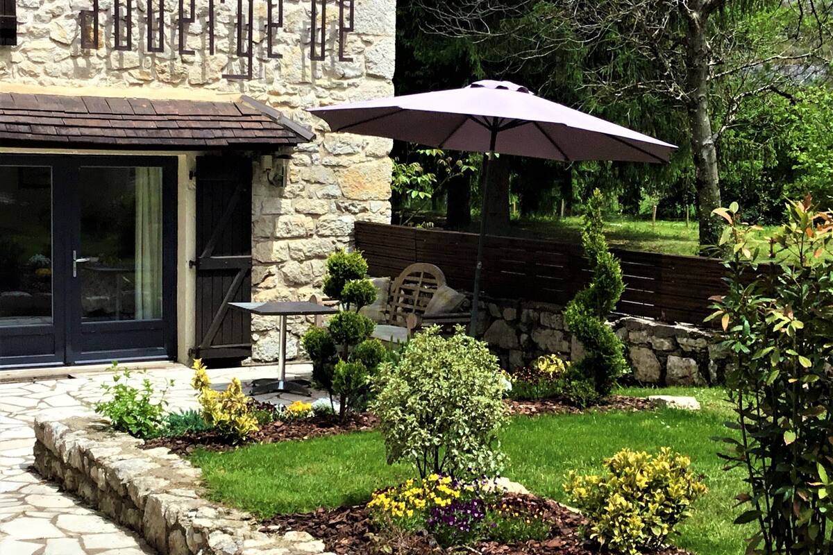 A stone building with a patio area featuring a table, chairs, and a large umbrella.