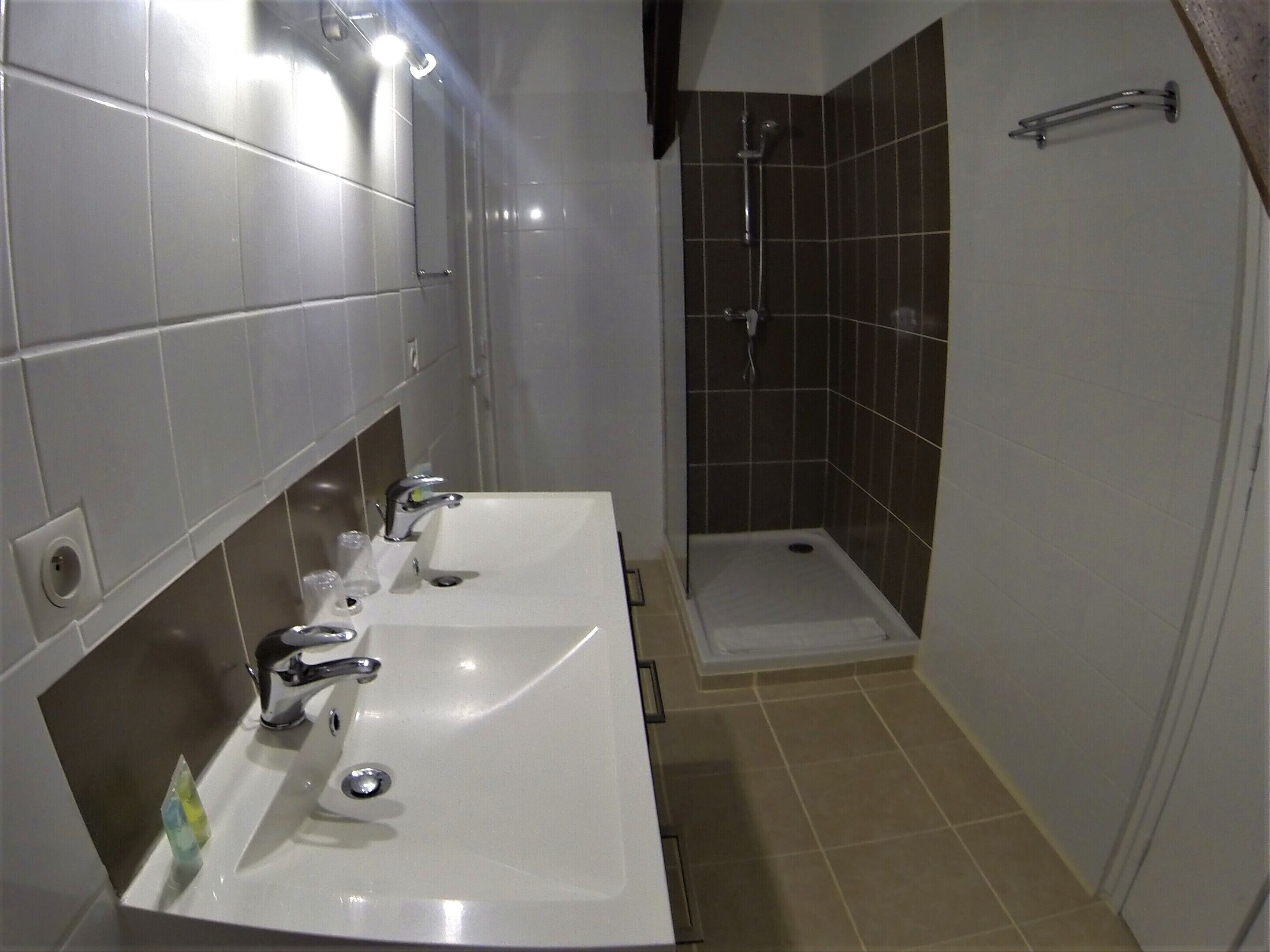 Un baño con dos lavamanos, una ducha y un perchero para toallas.