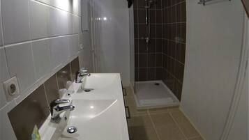 Un baño con dos lavamanos, una ducha y un perchero para toallas.