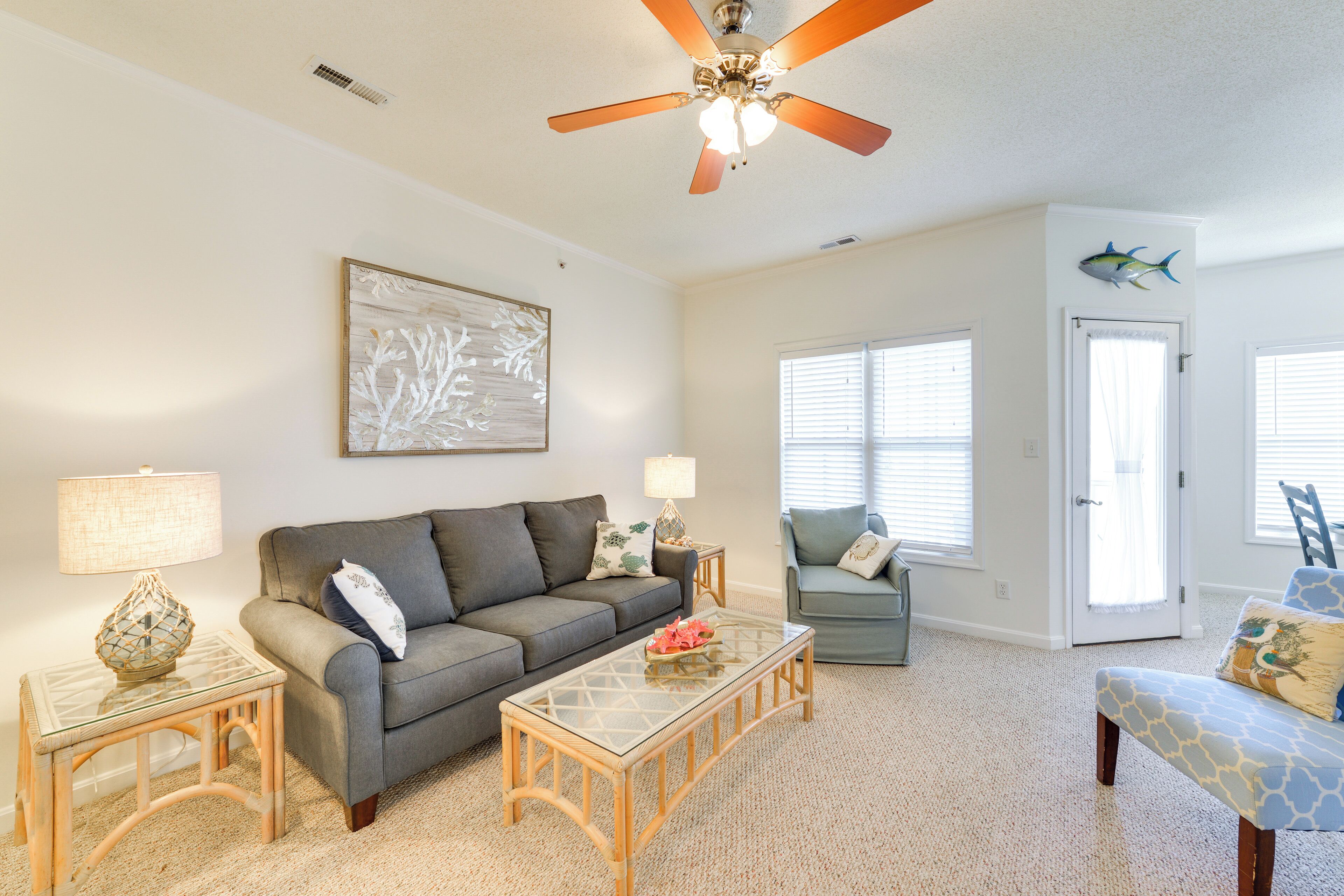 A living room with a ceiling fan, a sofa, a coffee table, and a chair.