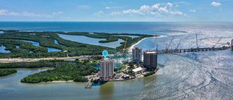 An aerial view of a coastal area with a marina, buildings, and a bridge.
