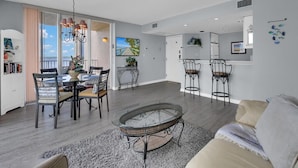 A modern living room with a dining area, a ceiling fan, and a view of the outdoors. - Spectacular Views!!  Beautifully Updated!!  No Resort Fees! (Fort Myers Beach)