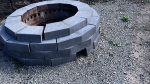 A circular stone fire pit in a garden with a stone wall, surrounded by gravel. - 10 minutes to FallingWaterand 15 minutes to Ohiopyle. Very Quiet !  (Mill Run)